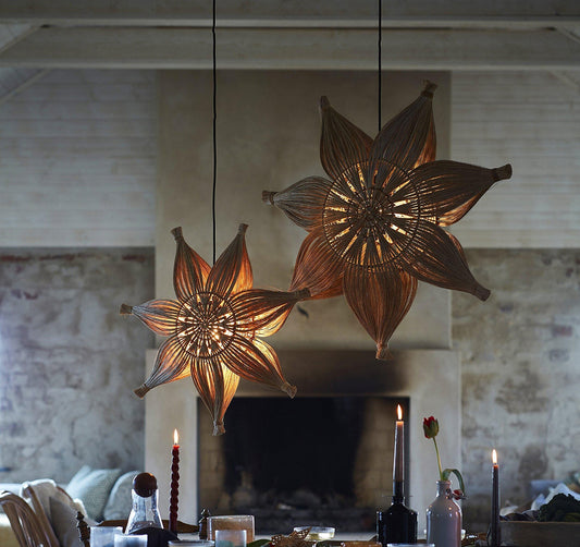 Hängande julstjärne-lampor i rotting ovanför dukat bord i mysig miljö