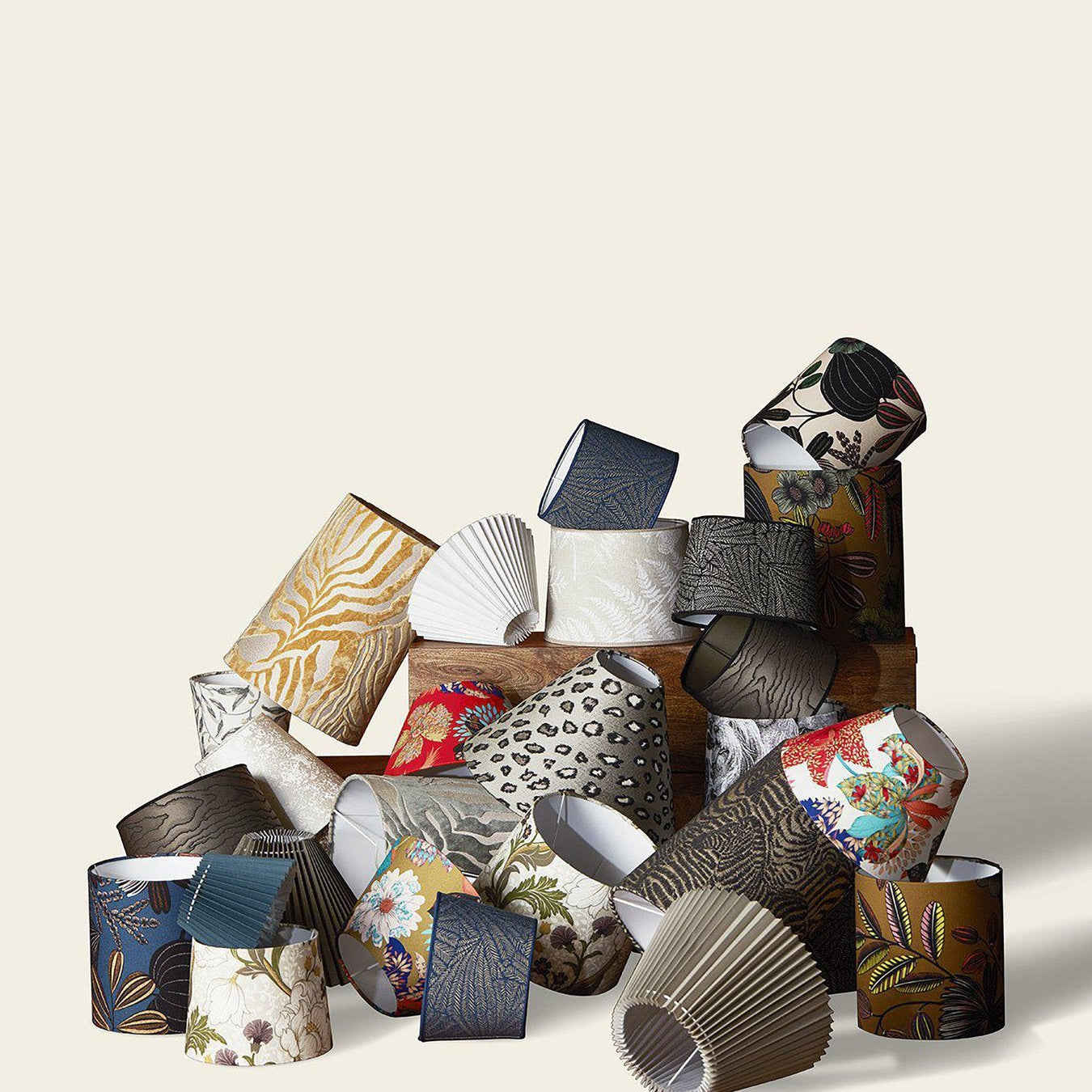 En hög av lampskärmar i olika färger och mönster, inklusive blommiga, djurmotiv och enfärgade designer.
