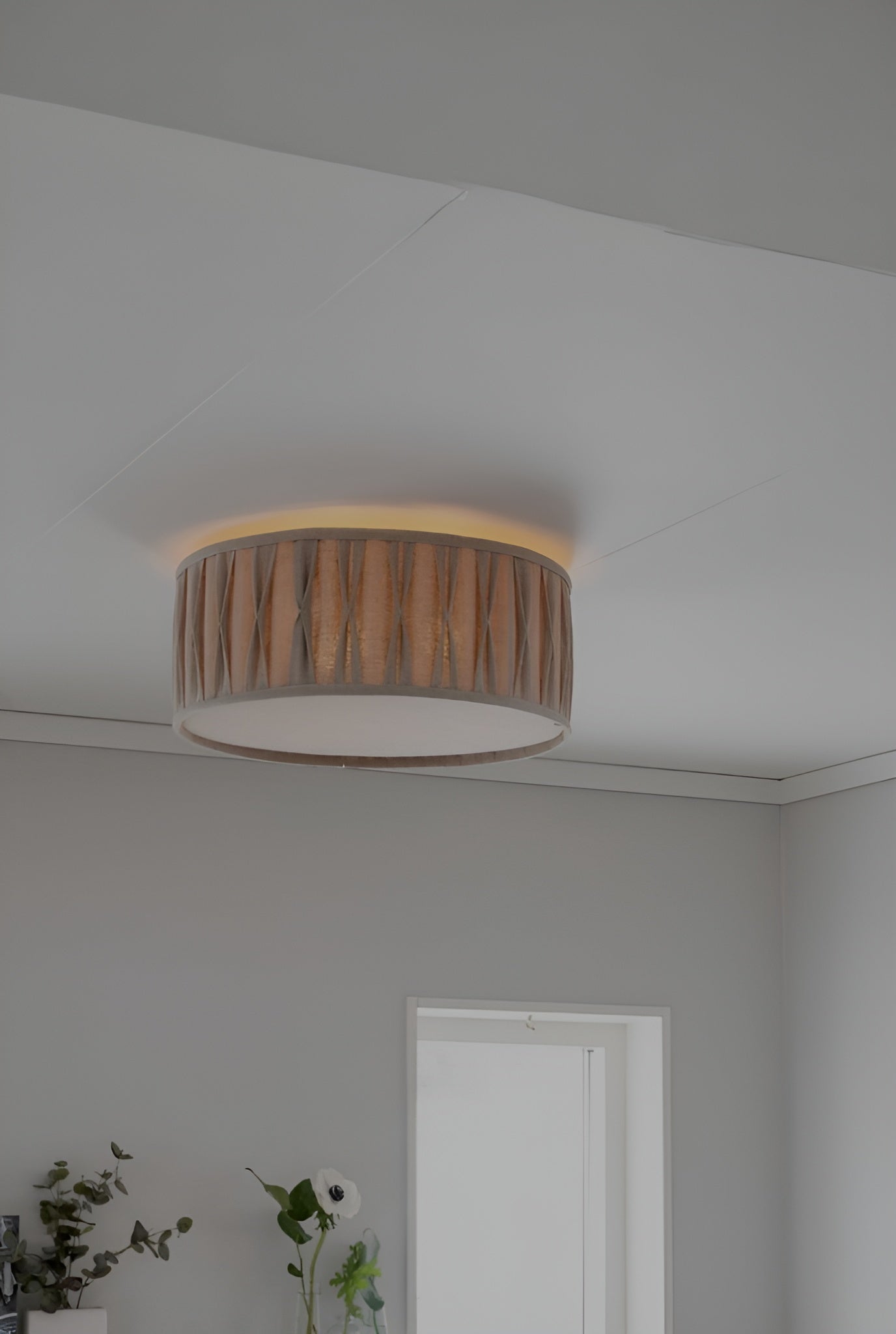 Rund plafond med trädetaljer monterad i vitt innertak i ett ljust rum med minimalistisk inredning.