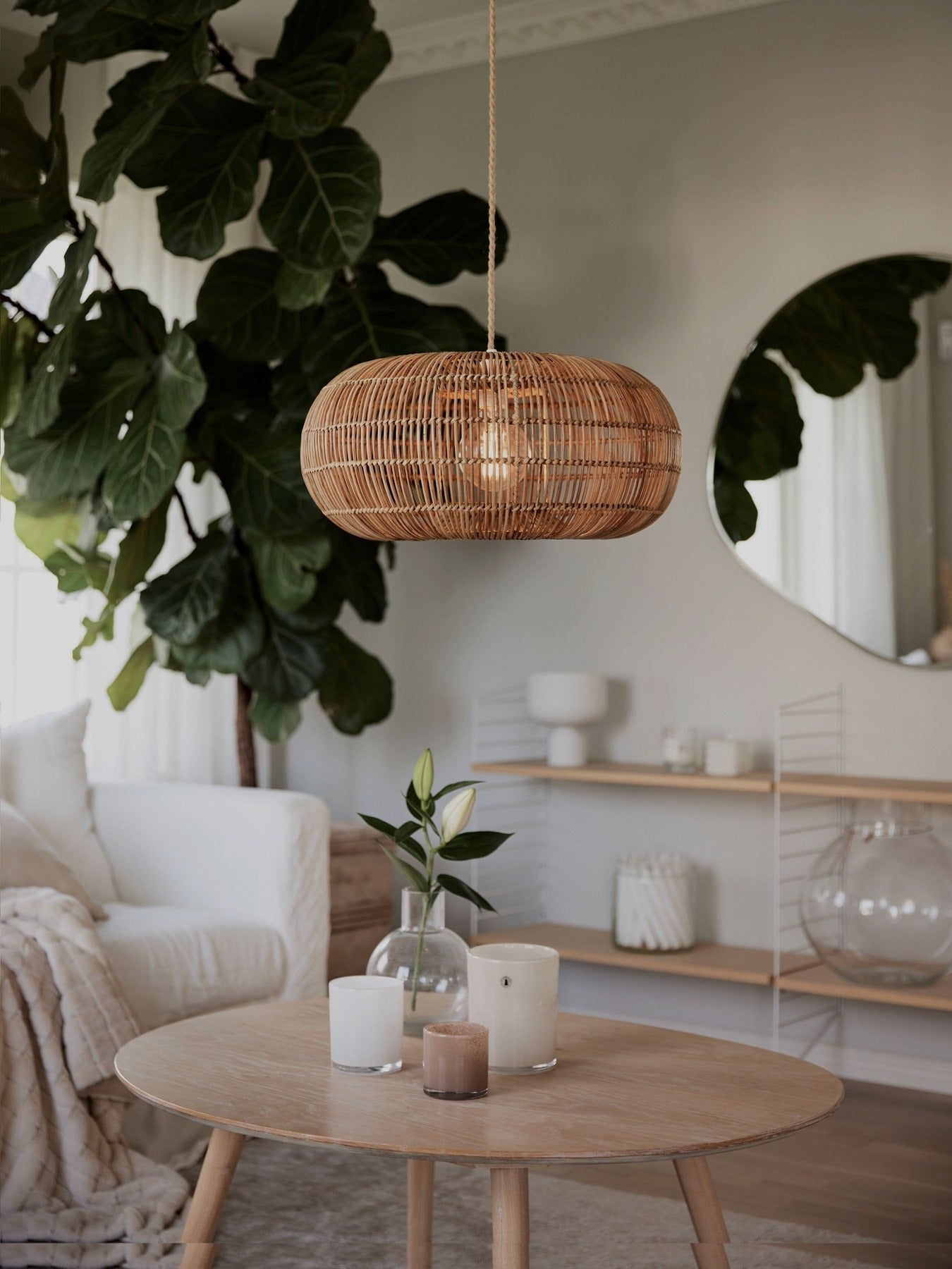 Taklampa i rotting ovanför ett runt soffbord i en harmonisk och ljus vardagsrumsmiljö