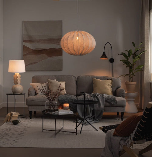 Vardagsrum med soffgrupp, golvlampa och stor taklampa i tyg