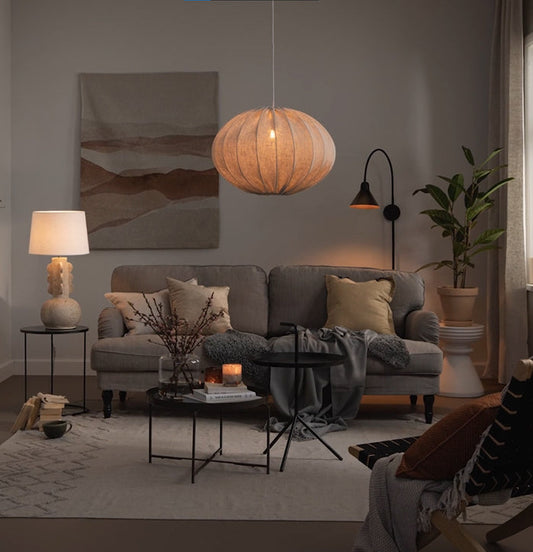 Vardagsrum med soffgrupp, golvlampa och stor taklampa i tyg